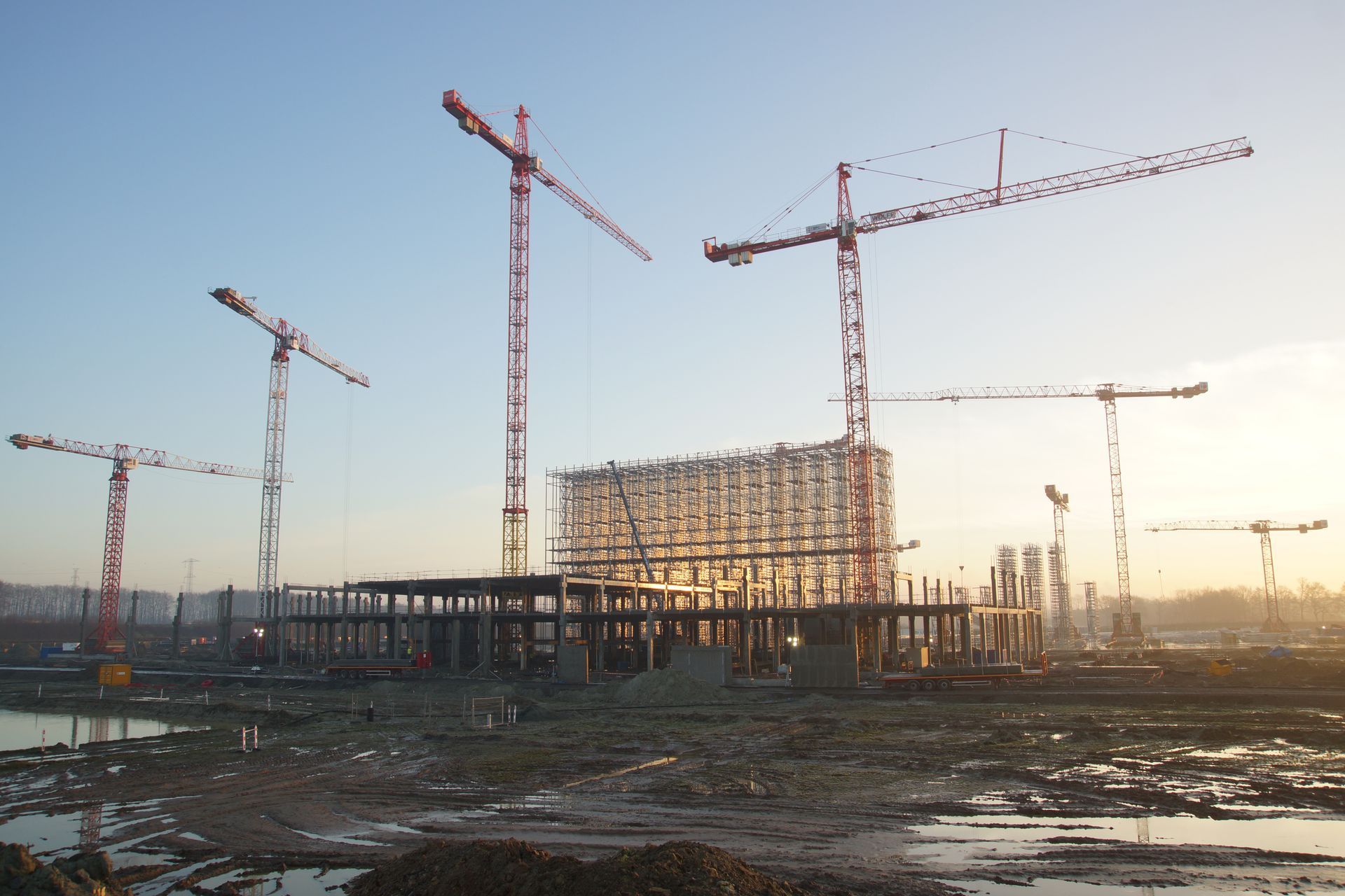 Tower cranes over a building frame on a large construction site at sunrise
